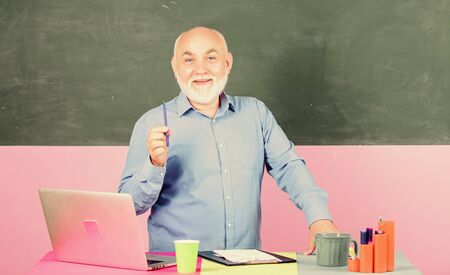 happy teacher. school lesson break. Mature teacher man with coffee cup. tutor in classroom. Making notes. senior man teacher with notebook and computer. back to school. Education conceptの写真素材