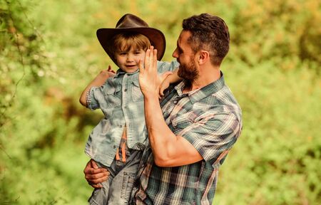 Strong like father. Power being father. Child having fun cowboy dad. Rustic family. Growing cute cowboy. Small helper in garden. Little boy and father in nature background. Spirit of adventuresの写真素材