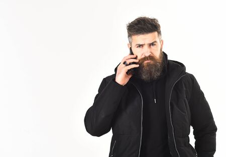 Man with serious face wears warm clothes and holds mobileの写真素材