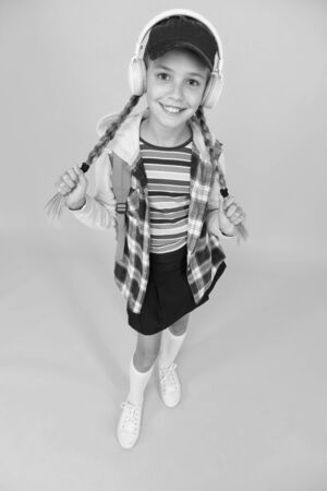Cool schoolgirl. Teens fashion. Teenager lifestyle. School days. Modern teenager. Happy childhood. Cute hipster teenager kid yellow background. Cheerful teenager. Small child girl long hairの写真素材