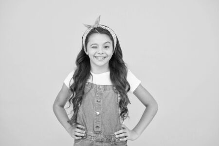 cute lovely kid. hairdresser salon concept. little beauty long curly hair. retro girl smiling yellow background. small child vintage look. summer kid fashion. beauty and fashion. happy childhoodの写真素材