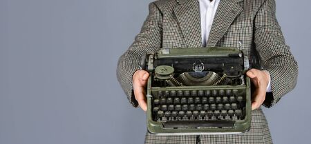 new technology in modern life. Man working on retro typewriter in library. mechanical vs digital. writer writes with typewriter. bearded man in jacket with retro type writer. copy spaceの写真素材