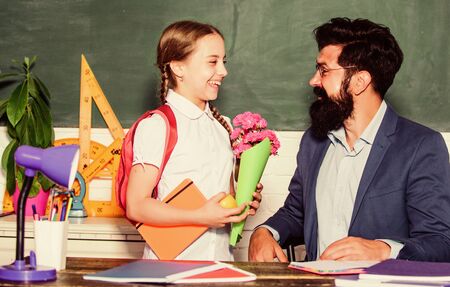 Knowledge day congratulations. School holiday. Thankful schoolgirl. Greetings for school pedagogue. Back to school. Best wishes. Girl adorable pupil with backpack giving bouquet flowers teacherの写真素材