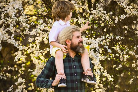 Spring walk. Simple happiness. Happy family. Fatherhood happiness. Fathers day. Little boy and father in nature background. Hipster and baby son. Exploring garden together. Happiness conceptの写真素材