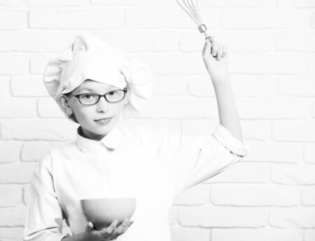 serious boy cute cook chef on brick wall backgroundの写真素材