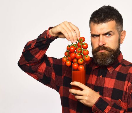 Farmer with serious face shows bunch of red cherry tomatoes.の写真素材