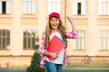 happy preschool girl with folder in school yard. back to school. hardworking child with book. concept of education. time to work hard. cute girl study outdoor. little smart student. Imagine greatnessの写真素材
