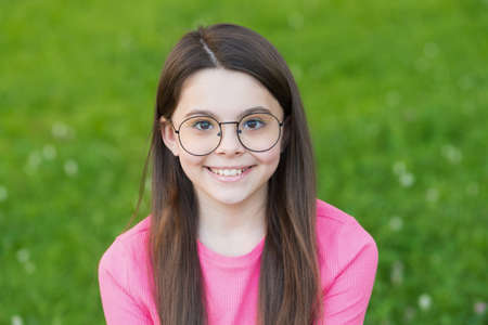 Little beauty with happy smile. Little child sit on green grass. Little kid relax on summer outdoor....