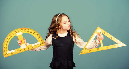 Pupil girl with big rulers. School student learning geometry. small girl back to school. STEM school disciplines. math lesson. Education and knowledge. Preparing to examsの写真素材
