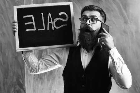 Bearded man, brutal caucasian hipster with smartphone holding sale inscriptionの写真素材