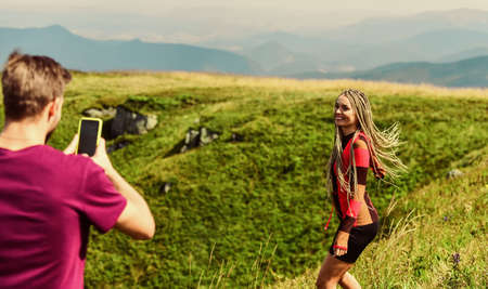 Young adventurers. Couple taking photo. Couple in love hiking mountains. Lets take photo. Capturing beauty. Man and woman posing mobile photo. Summer vacation concept. Travel together with darlingの写真素材