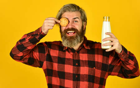 Happy hipster eat cookie dessert. Just happy. Favorite food. Recipe homemade cookies. Milk and sweet cookie. Delicious as in childhood. Mature bearded man drink milk with cookie. Breakfast traditionの写真素材