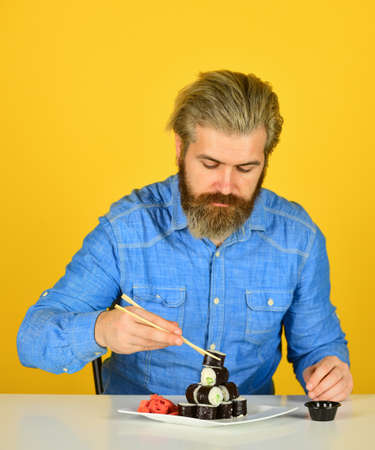 man eating traditional Japanese food with chopsticks. dinner at home. hipster eat sushi with...
