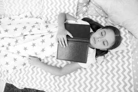 Leave me to dream. Little child fell asleep reading book. Small kid see dream in bed. Cute daydreamer. Dream work. Child imagination and fantasy. Following dream. Reading good for sleepの写真素材