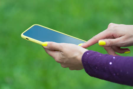 Using mobile app. Mobile phone in female hands. Smartphone with touchscreen. Mobile device. New technology. 4G. 3G. SMS. Mobile communication. Social marketing. Buy online. Cyber monday. Modern lifeの写真素材