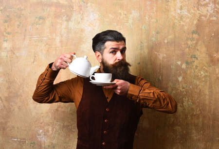 Waiter pours tea into white tea cup from potの写真素材