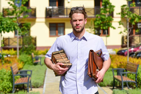 Man with briefcase and pile of old books in yard