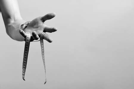 Hand of man holding blue measuring tape on purple backgroundの写真素材