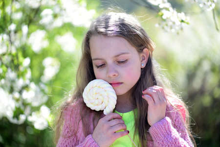 Schoolgirl with candy walks outside near blooming trees
