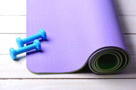 Sports and healthy lifestyle concept. Dumbbells made of cyan plastic on light wooden background....