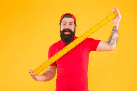 Post office worker with ruler. Big size. Measuring tool. Man holding ruler on yellow background....