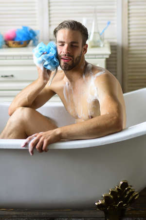 Sexuality and relaxation concept: bearded man washing with spongeの写真素材