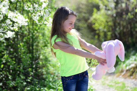 Kid in green tshirt holds pink bunny toy