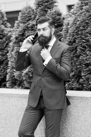 Stay connected. Businessman talk mobile phone. Handsome bearded man with cell phone outdoor. Mobile lifestyle. Business communication. Mobile technology. Business call. Stylish guy wear tuxedoの写真素材
