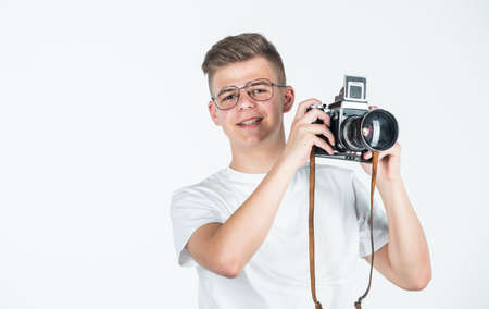 need closer look. travel photo concept. boy in casual wear with vintage photo camera. retro photographing. student photographer isolated on white. digital camera technology. young teen reporterの写真素材