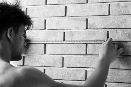 Man measures wall with measuring tape.