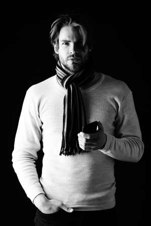 Macho with beard and stylish hairstyle, wearing scarf, holds cellphoneの写真素材