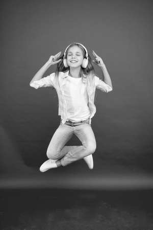 Modern child. Perfect sound. Never ending joy. So much fun. Girl listening music modern gadget. Kid happy with wireless headset dancing jumping. Stereo headphones. Kid using modern technologyの写真素材