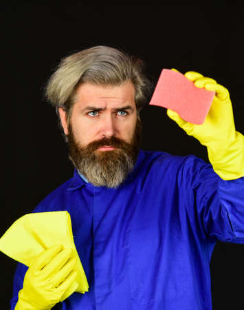bearded man in yellow rubber gloves wiping dust using duster.