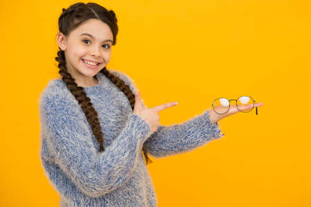 stylish teen has good vision. teenage girl presenting product. vision correction treatment. kid fashion and beauty. small girl hold glasses. childhood happiness. beautiful braided long hairの写真素材