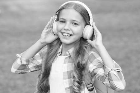 Audio book concept. Studying audio lessons. Listen music while walking. Girl headphones listening music. Educational podcast. Kid girl enjoy music. Pleasant time. Child headphones listen musicの写真素材