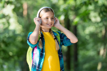 Essential part of modern life. Little girl wear headphones natural outdoors. Small child listen to...