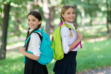 Positive mood. teenage girls with backpacks walking in park. Back to school. Teen kids with...