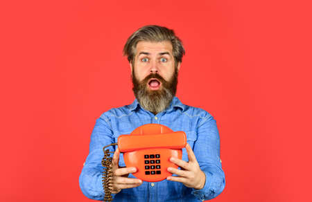 Man with moustache holding vintage phone.