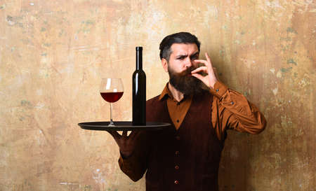 Man with beard holds wine on beige wall background.の写真素材