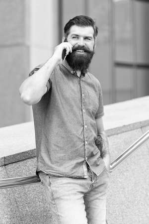 Modern life. Agile business. Call taxi. Mobile communication. Got it. Business conversation. Man with smartphone. Stylish handsome man with bristle outdoors. Man wearing casual shirt hold smartphoneの写真素材