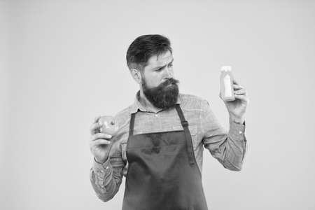 Vegetarian nutrition. Smoothie drink. Delivering fresh vitamins. Hipster smoothie beverage. Fresh juice. Squeezing smoothie. Man bearded chef hold organic natural tomato and bottle yellow backgroundの写真素材