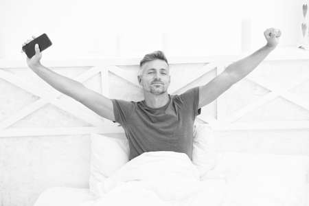 Modern life. Self isolation and quarantine. Stay home. Morning. Online communication. Mature man use mobile phone in bed. Mobile communication. Cellular communication. Communication technologyの写真素材