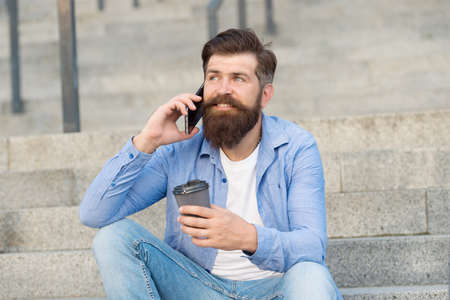 Pleasant conversation. Real connect. Drink coffee while talking. Modern urban life. Bearded man phone conversation. Mobile conversation. Coffee break. Personal communication. Calling friendの写真素材