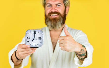 Wake up in morning. Time concept. Sleepy man hold alarm clock. Noise of alarm clock. Man awake with...