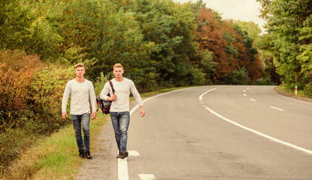 First and foremost. traveler hitchhiking on highway. on the way home. future. twins walking along...