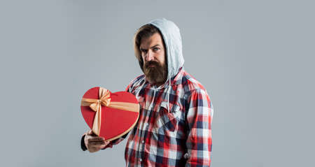 happy valentines day. heart is symbol of love. bearded man casual style hold gift box. time for presents. love holiday and vacation. birthday surprise for her. anniversary of marriageの写真素材
