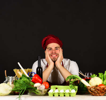 Food preparation concept. Cook sits in kitchen near tableの写真素材