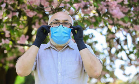 look fully protected. smell blooming flowers on coronavirus quarantine. observe precautions while...