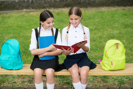 help and support. children read notebook for making notes. happy childhood. back to school. teen pupils ready for lesson. prepare to exam. study together outdoor. small girls with books and backpacksの写真素材