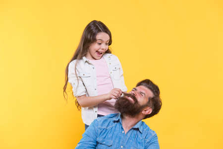 My father is hipster. Little girl pull hipster beard. Happy family yellow background. Hipster...